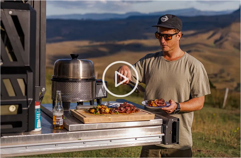 Cobb Grill cooking setup on MRT canopy drawer system with man preparing food in remote highland location